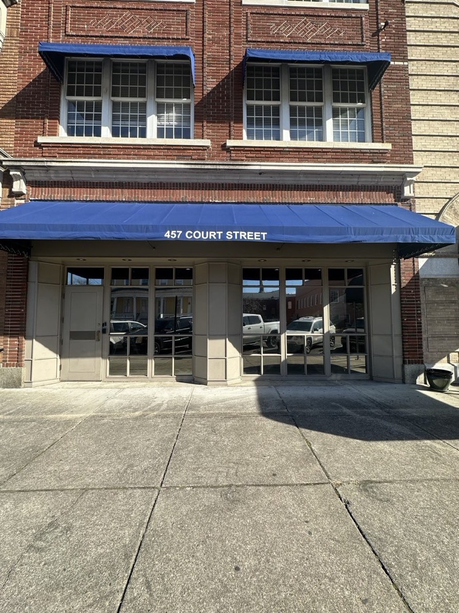 Brick storefront with blue awnings and film on the ground-floor glass