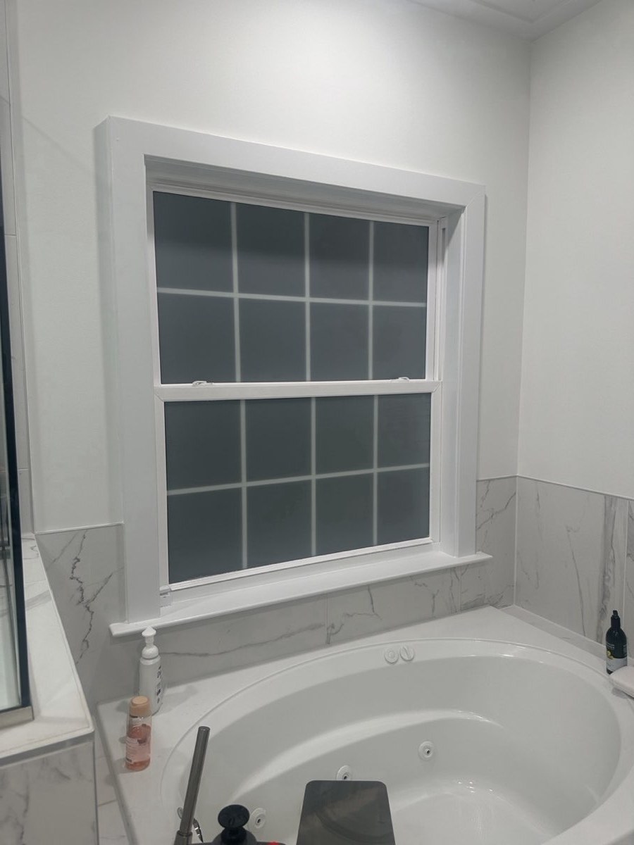 Bathroom window with frosted privacy film above a bathtub