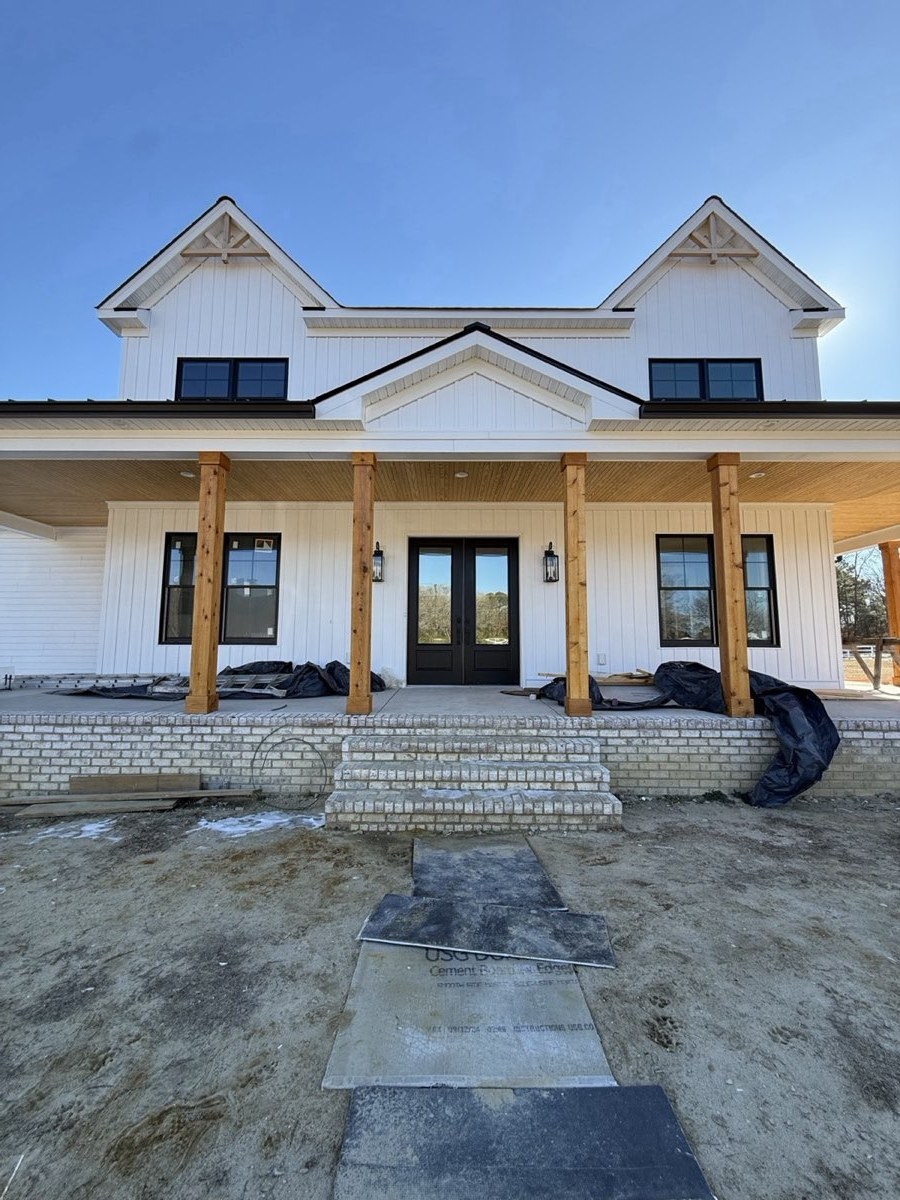 New white farmhouse-style home with film on the front windows and doors
